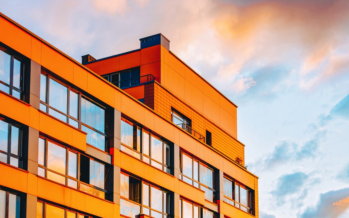 Modernes Wohngebäude mit oranger Fassade vor blauem Himmel