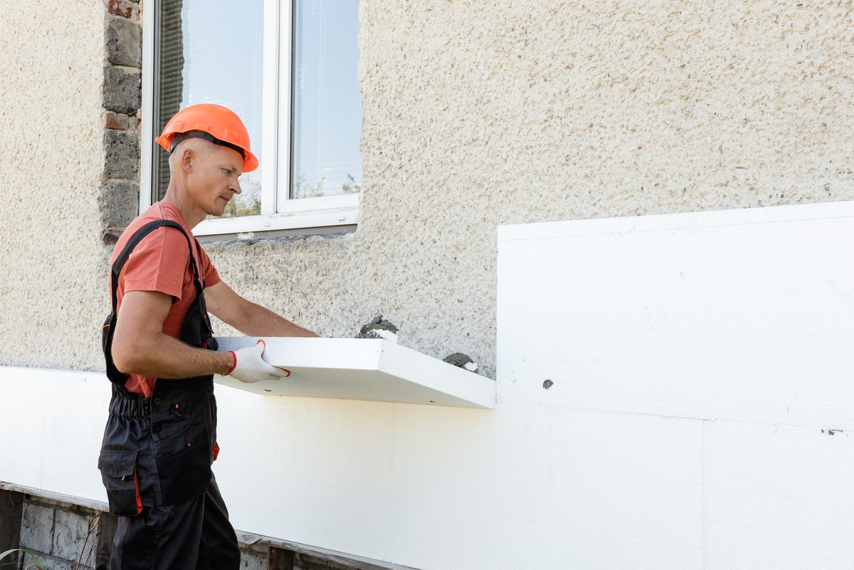 Handwerker bringt eine Dämmplatte an einer Fassade an